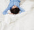 Woman with blue pajamas laying on white premium Down Comforter.
