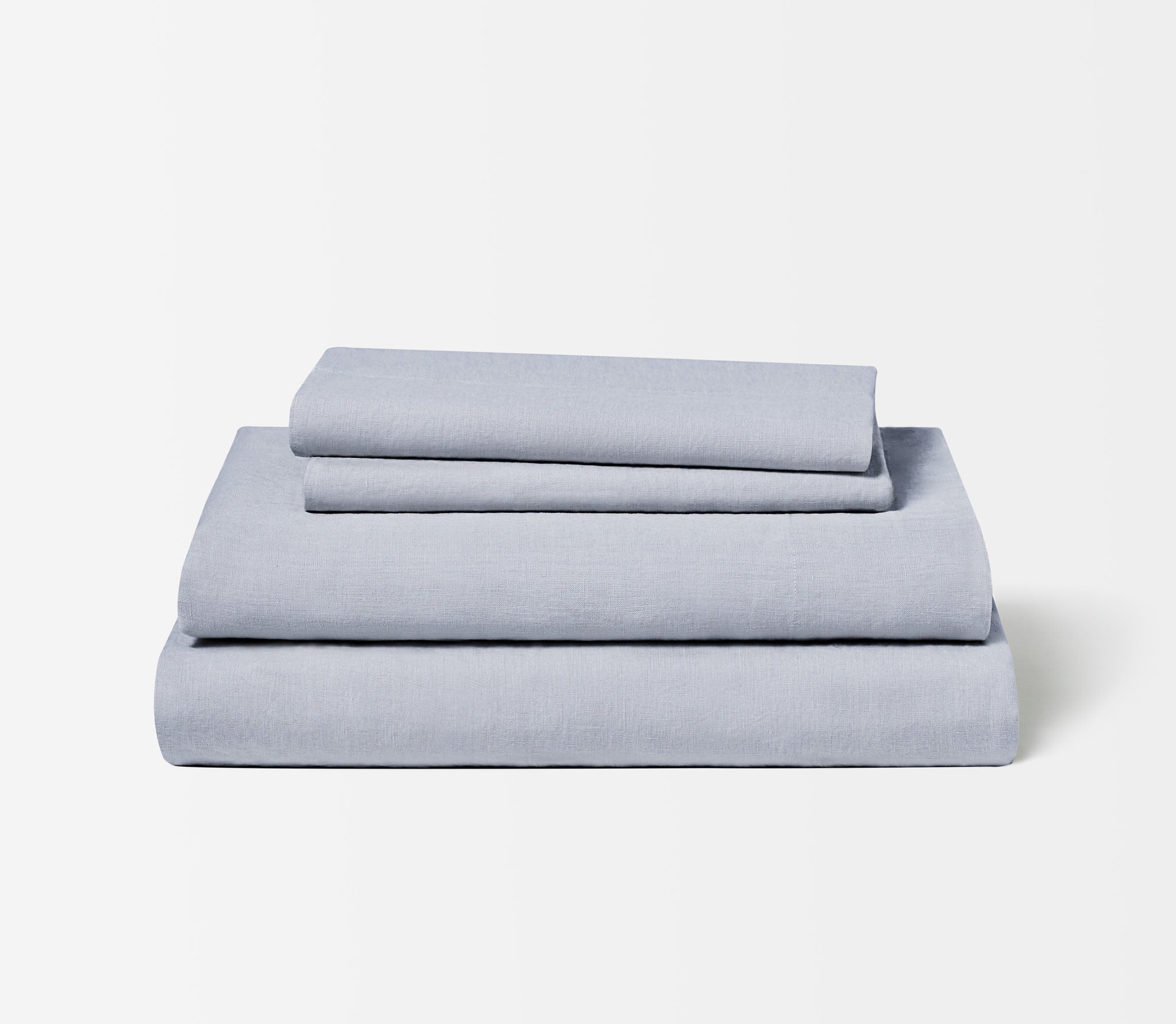 Folded set of two Slate Blue Linen Pillow Cases on top of a folded Linen Fitted Sheet and Flat Sheet.