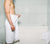 Man standing in white bathroom wrapped in a Essential White Classic Bath Towel.