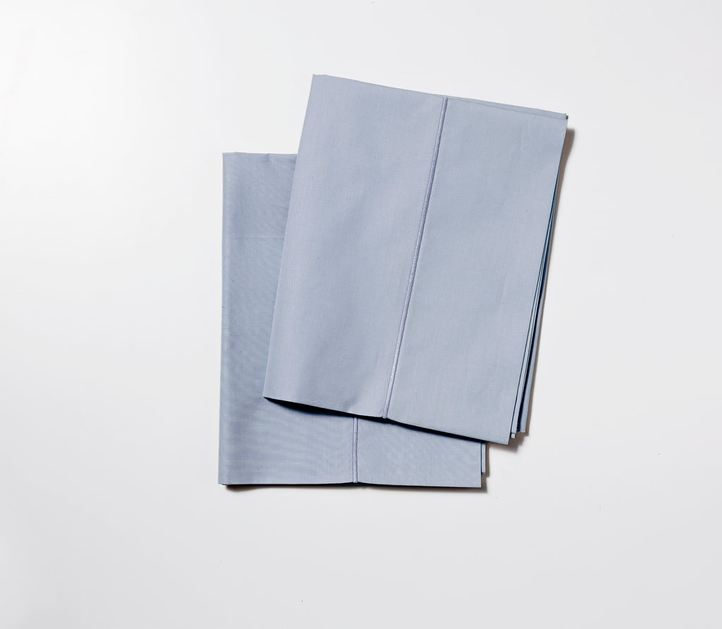 Two folded Slate Blue Percale Pillow Cases with white background.