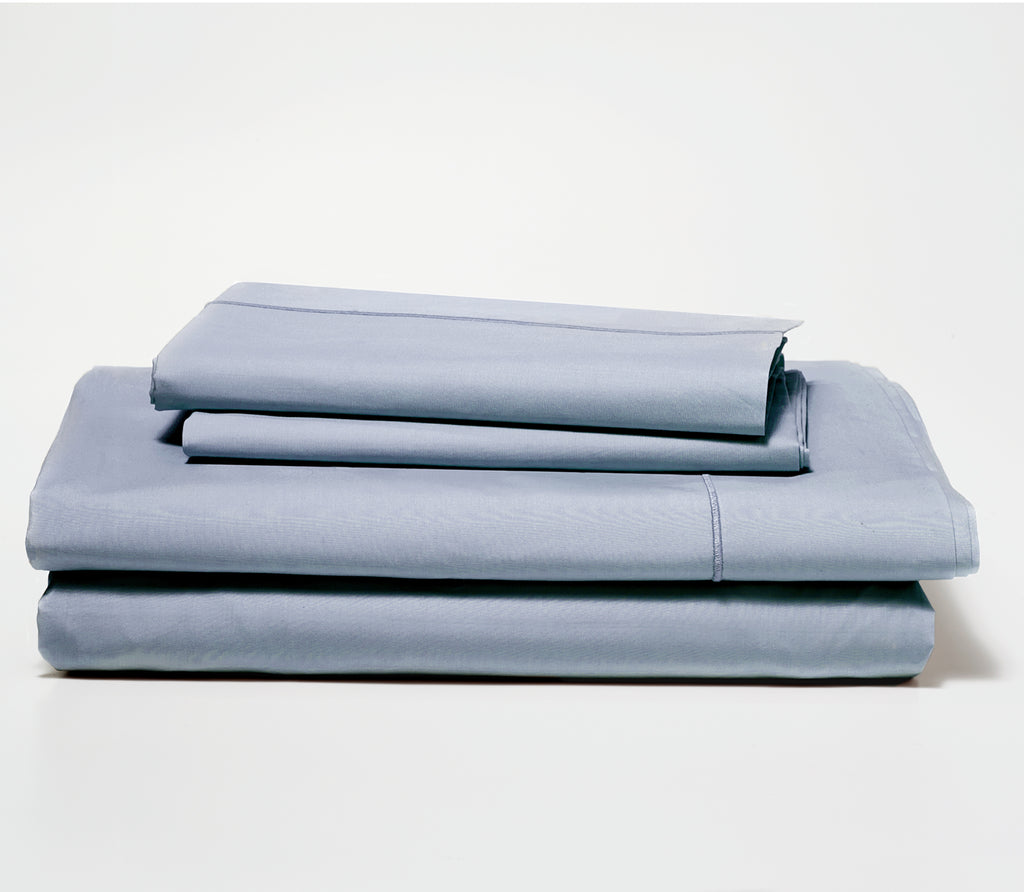 Folded set of two Slate Blue Percale Pillow Cases on top of a folded Percale Fitted Sheet and Flat Sheet.