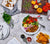 White tablescape featuring End-Grain hand crafted, black walnut, rectangular cutting board with various other food dishes around it.