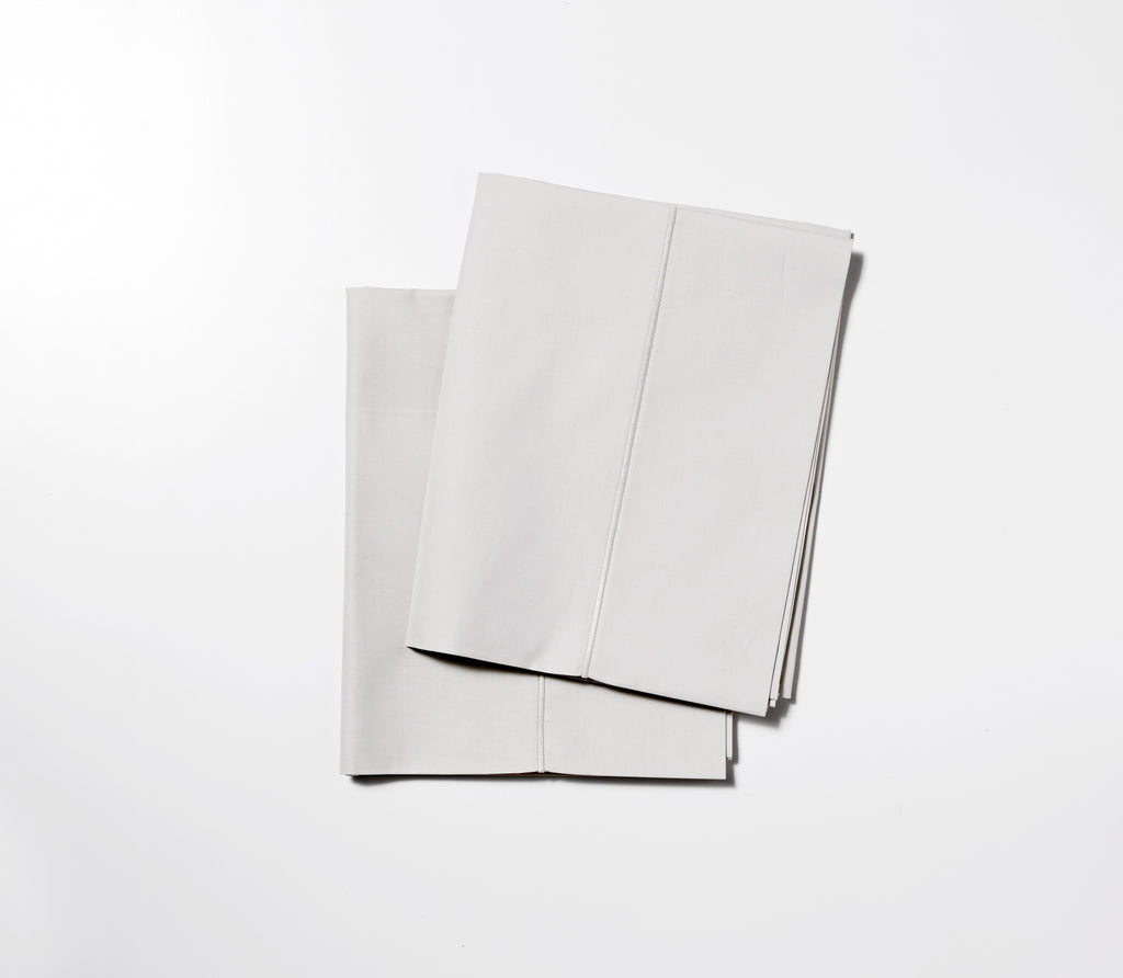 Two folded Ash Grey Percale Pillow Cases with white background.