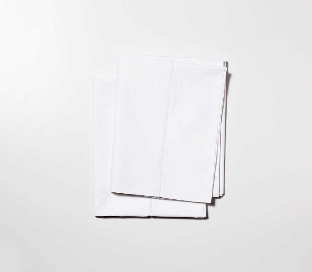 Two folded Essential White Percale Pillow Cases with white background.