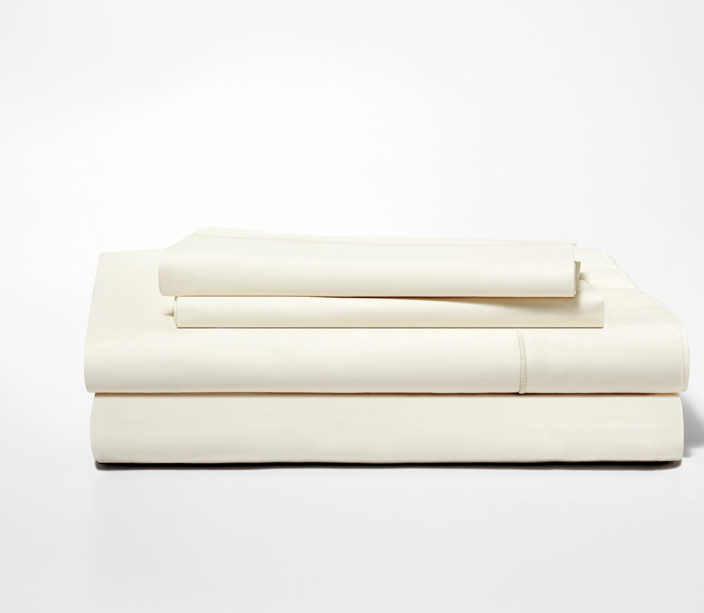 Folded set of two Classic Ivory Percale Pillow Cases on top of a folded Percale Fitted Sheet and Flat Sheet.