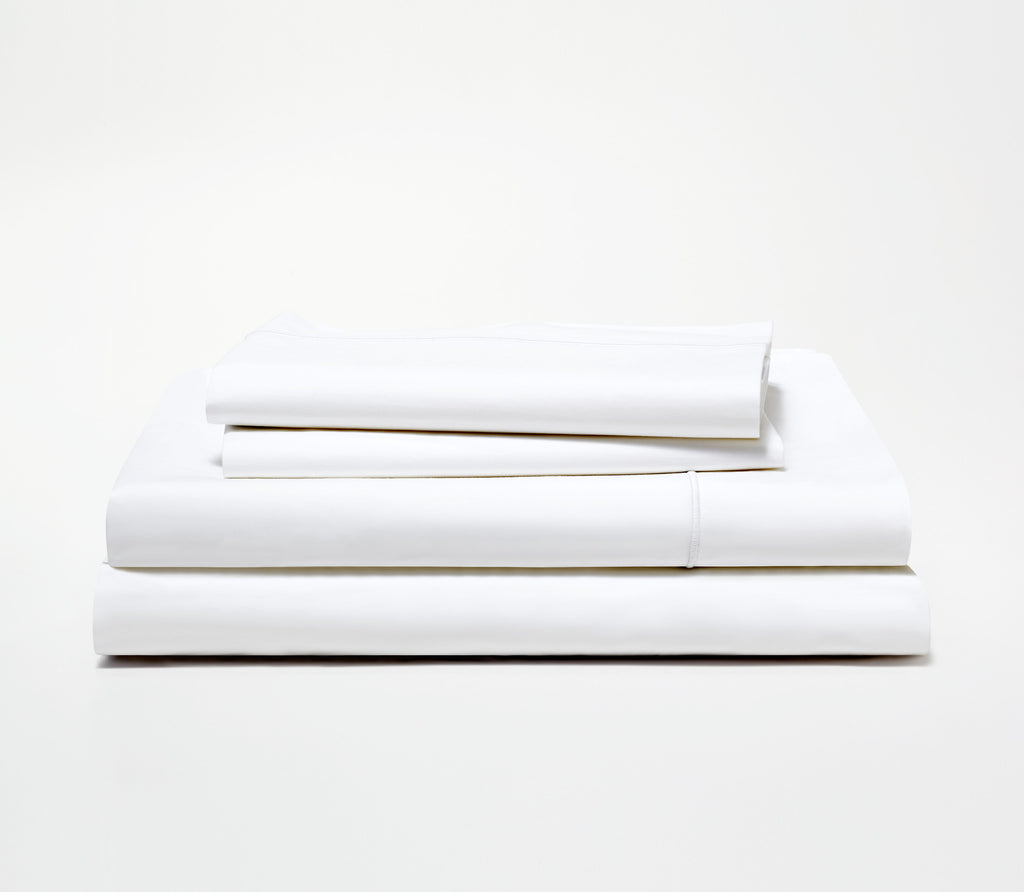 Folded set of two Essential White Percale Pillow Cases on top of a folded Percale Fitted Sheet and Flat Sheet.