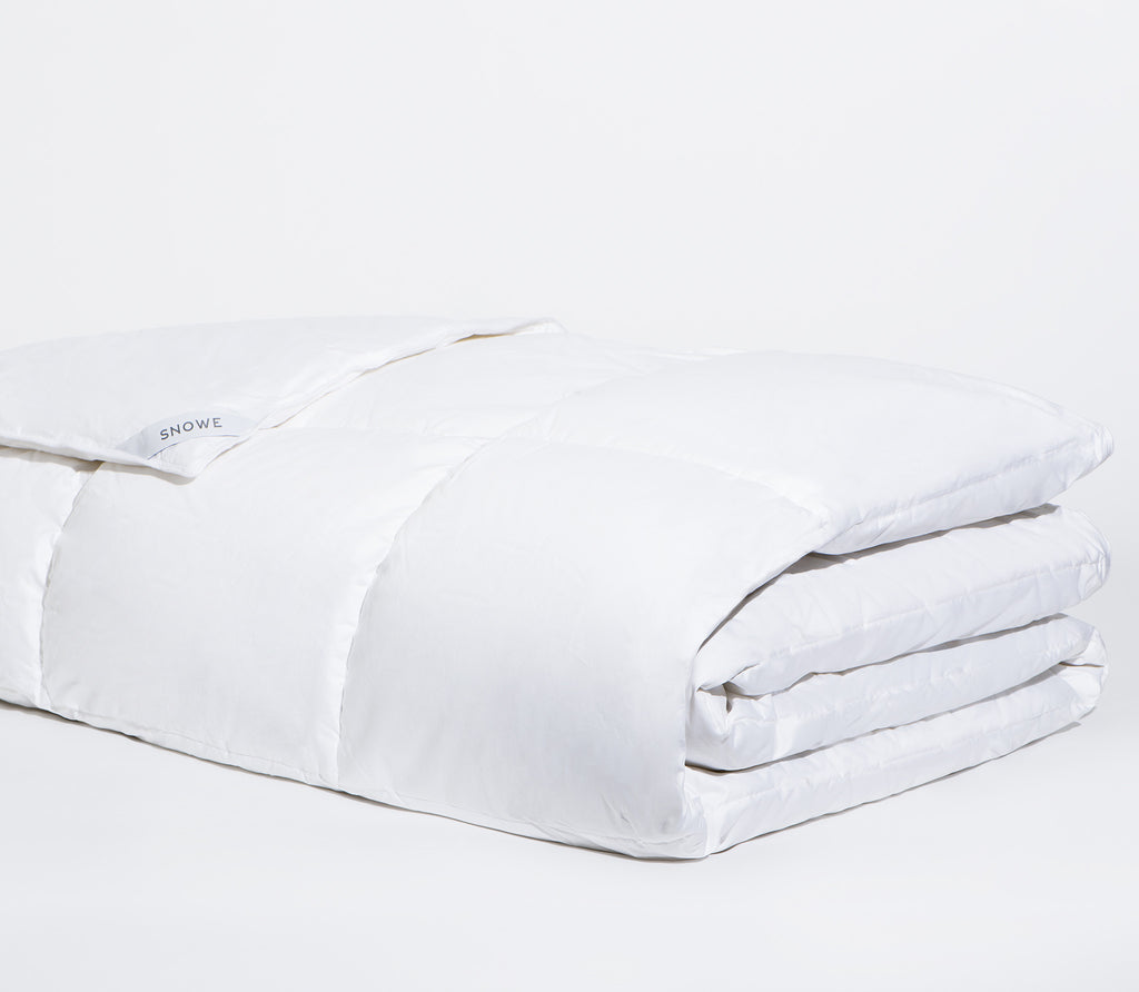 Zoomed in shot of folded white Down Alternative Comforter with white background.