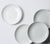 Top view of four white porcelain dinner bowls with white background.