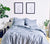 Bed dressed in Slate Blue Percale bedding with bedside tables and decorative items around.