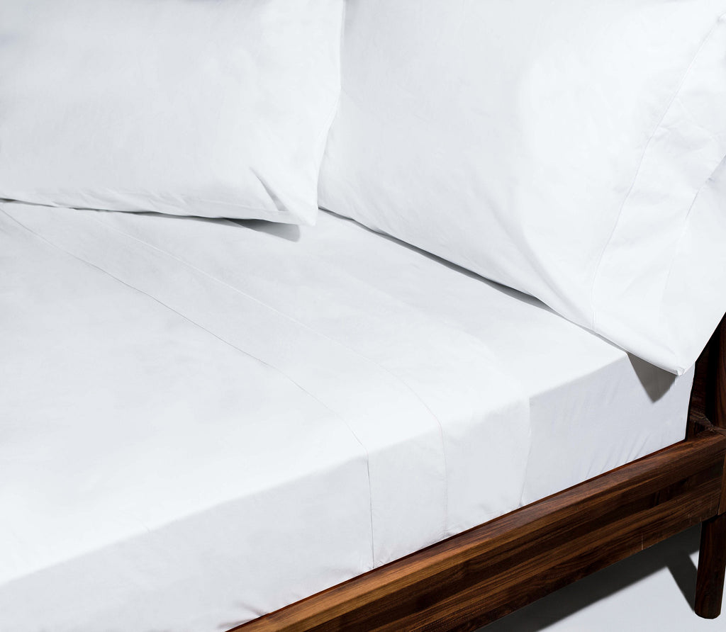 Essential White Percale Sheets with pillows in pillowcases on a brown bed